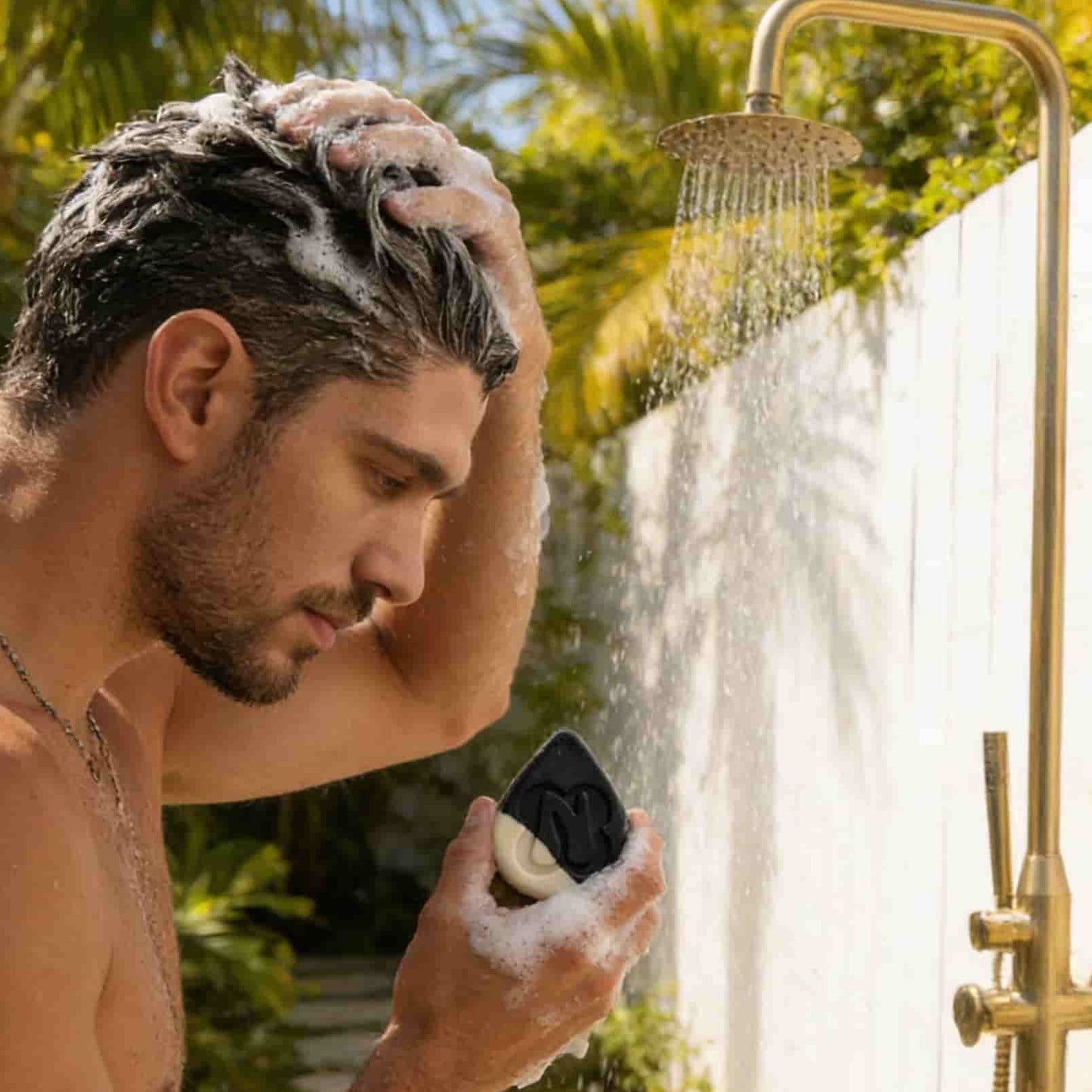 Man under shower with bubbly lather using The Balancer charcoal detox shampoo bar for oily roots